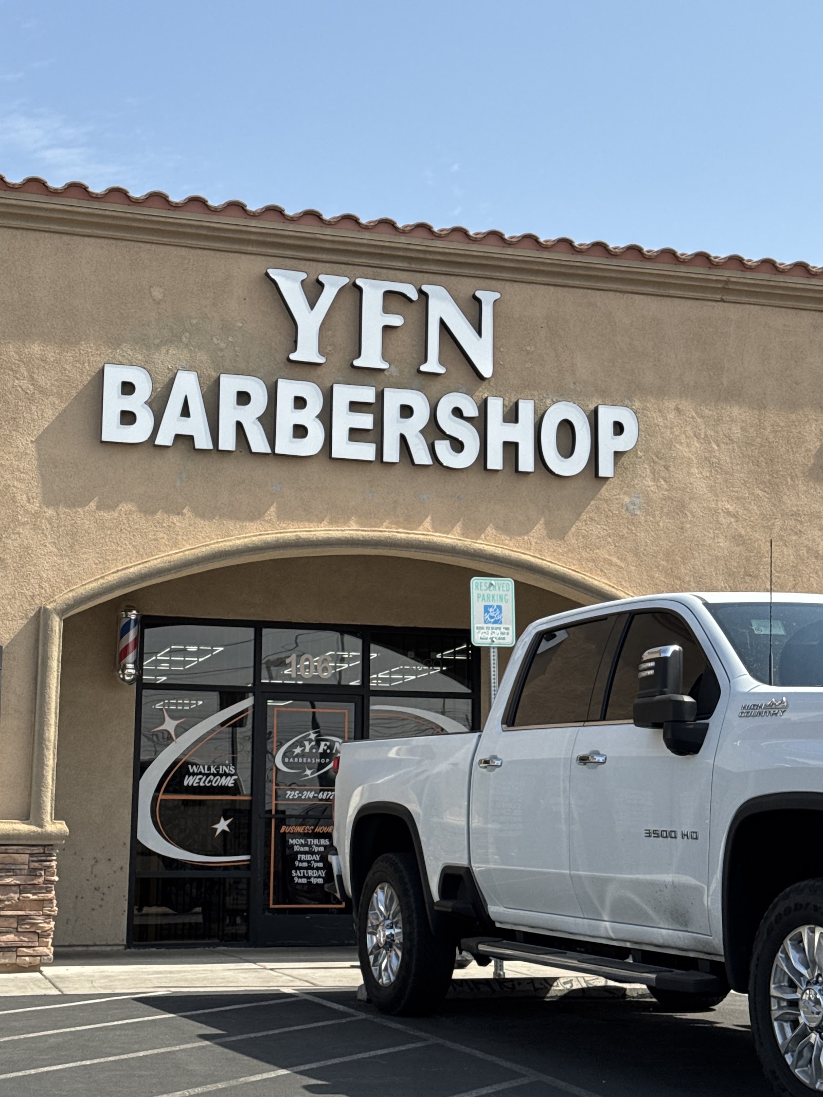 Close-up of YFN Barbershop exterior sign with white truck parked in front