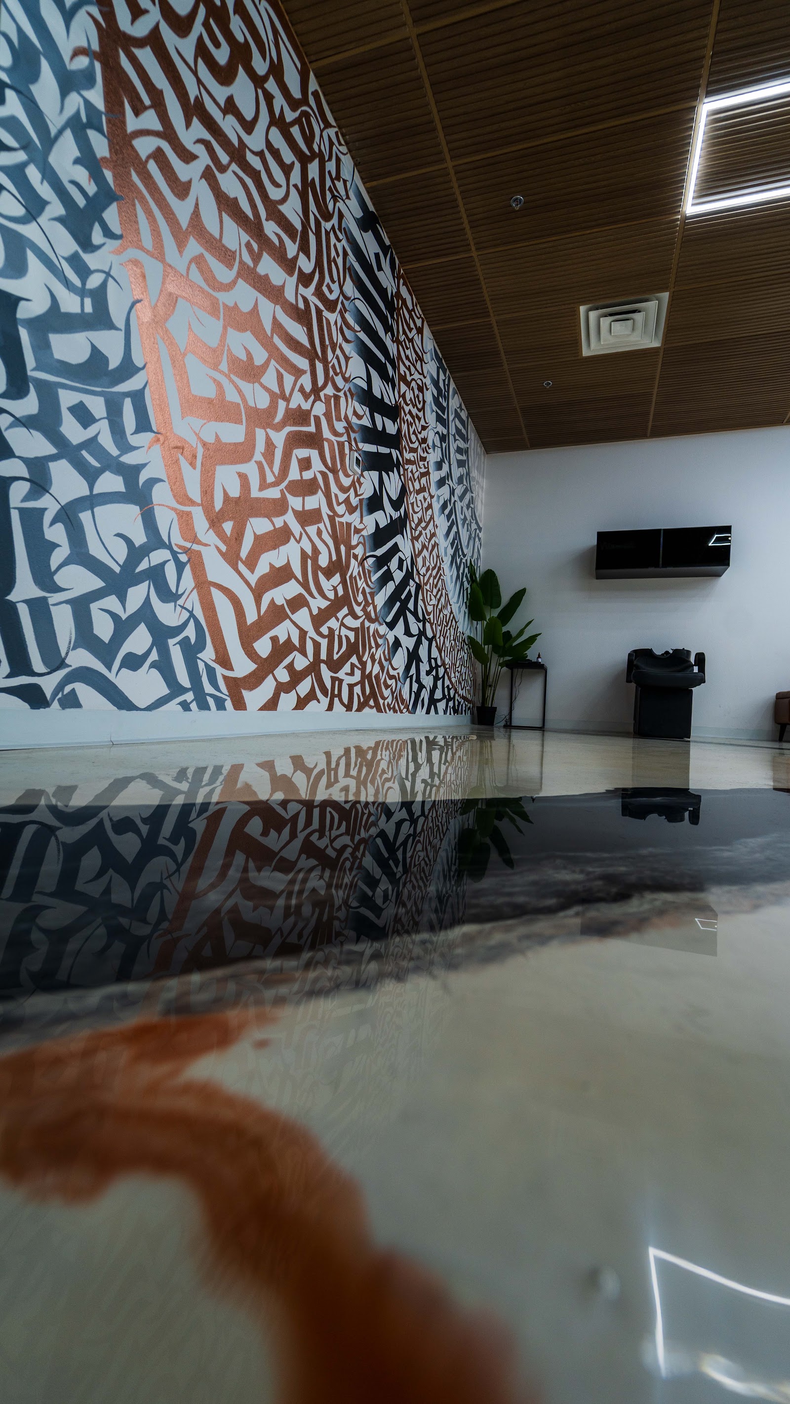 Barbershop wall with large calligraphy mural and reflective floor